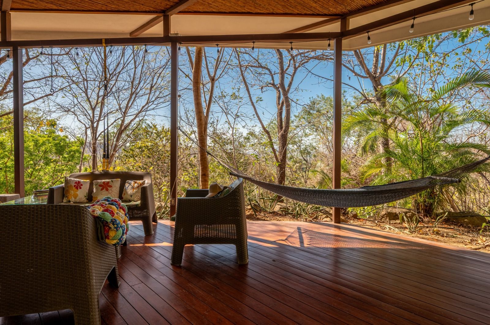 Patio with hammock strung between posts, jungle beyond